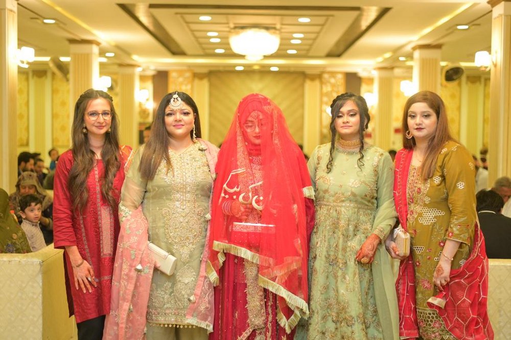 Four women and the bride wearing traditional wedding costumes during a wedding in Pakistan