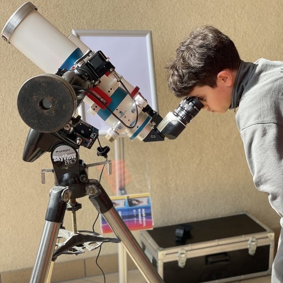 a child watching the sun eclipse through a telescope
