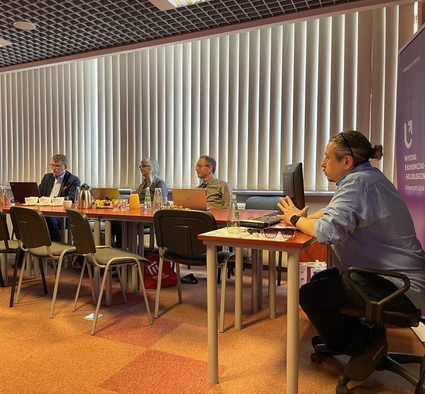  a group of people sitting at tables with refreshments and laptops