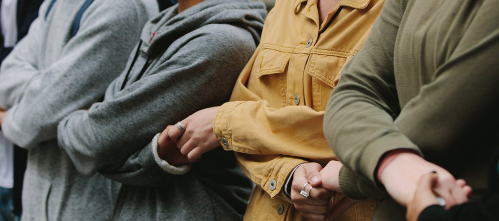 Osoby stojące w rzędzie obok siebie i trzymające się za ręce