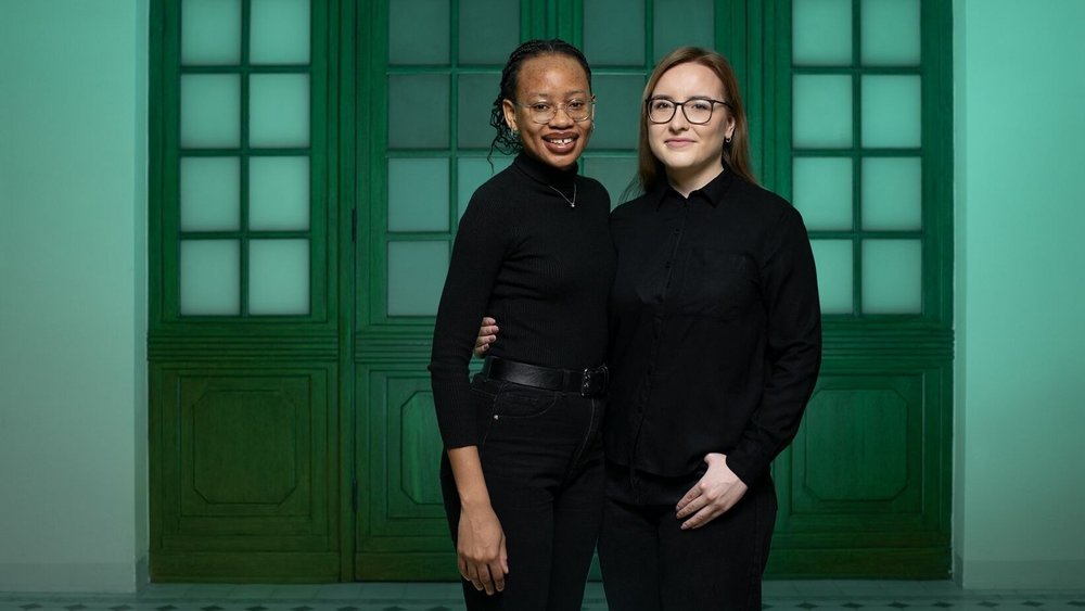 Two female students, i.e. UNIC Ambassadors at the University of Lodz, standing side by side on a green background