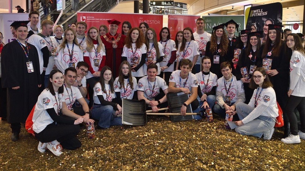 Members of the Student Science Club Inwestor standing in front of a large heart made of gold coins
