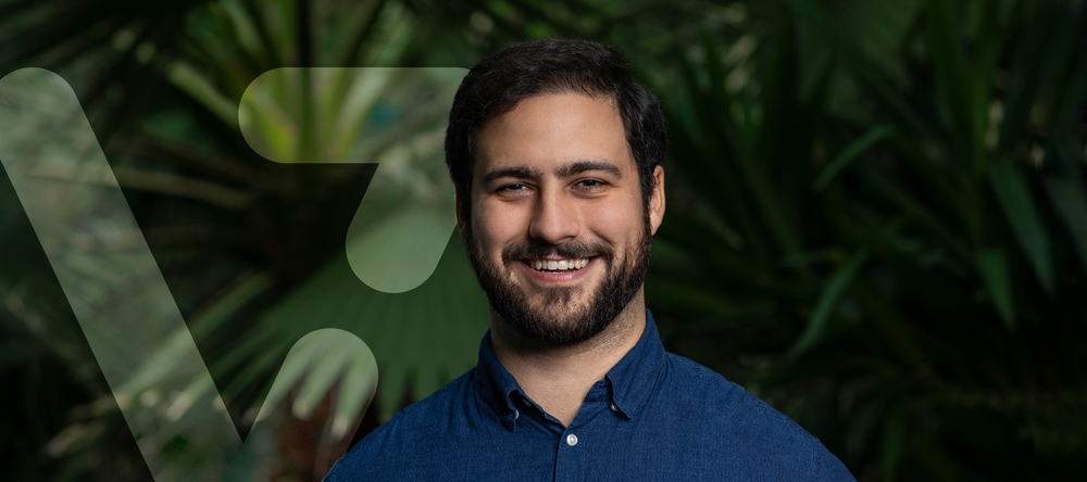 uśmiechnięty dr Naziris obok grafiki przypominającej literę V