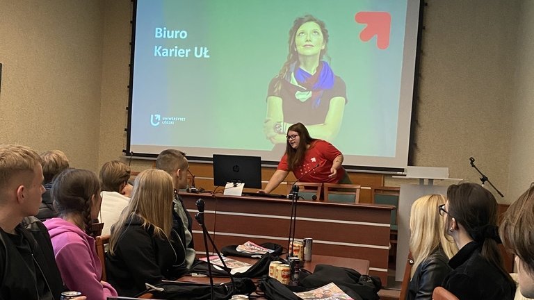 Studentka prezentuje uczelnię w sali wykładowej