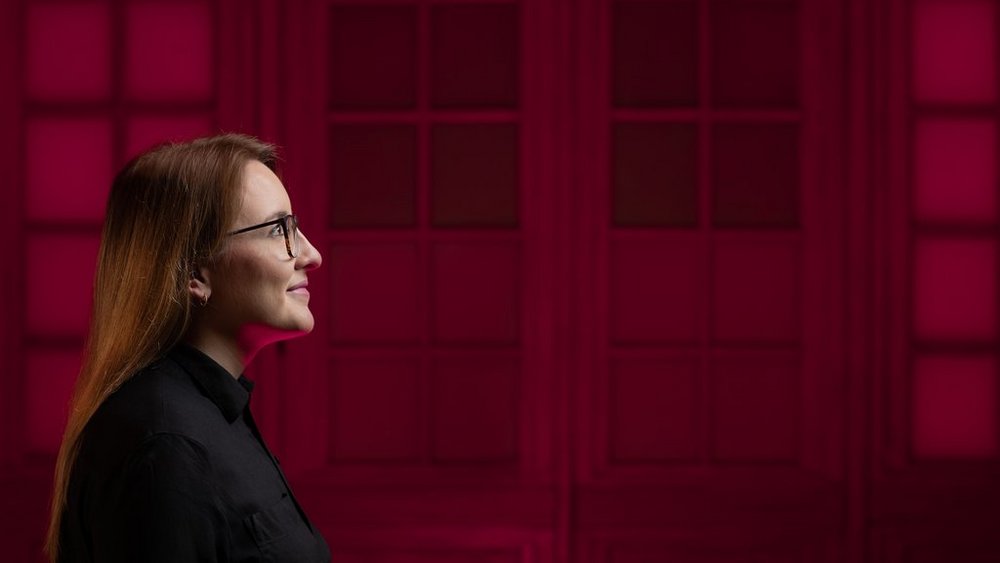 The photo shows the profile of a student on a red background.