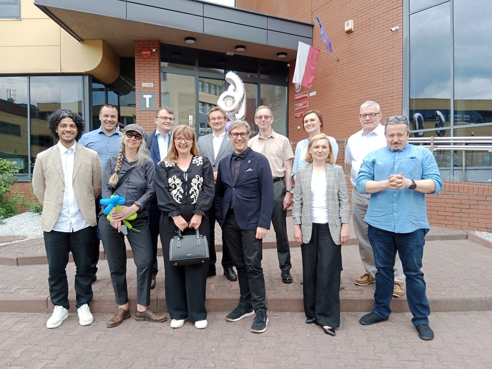 a group of smiling people in elegant clothes standing in front of the university building