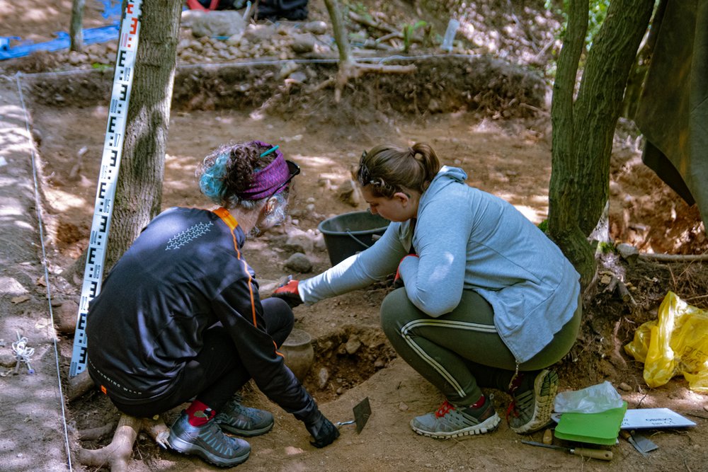 Dwie osoby pracujące przy jamie na wykopaliskach