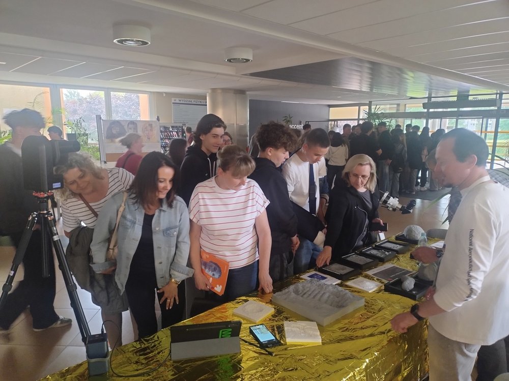 participants of the Science Picnic, a group of students and teachers observing a stand with physics demonstrations
