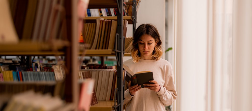 A girl reading a book in a library