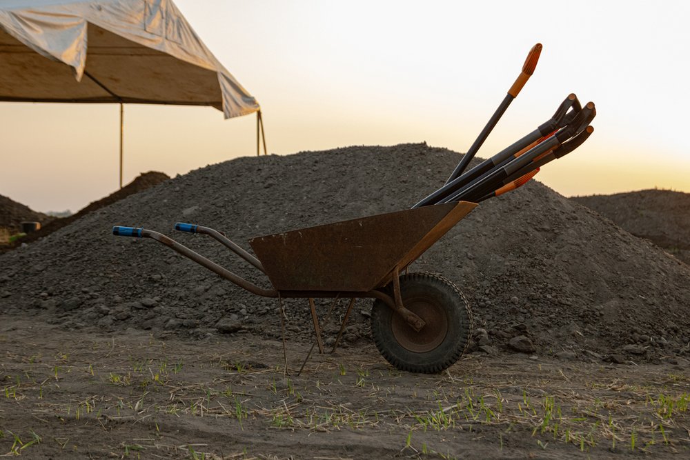 taczka z łopatami na tle hałdy ziemi
