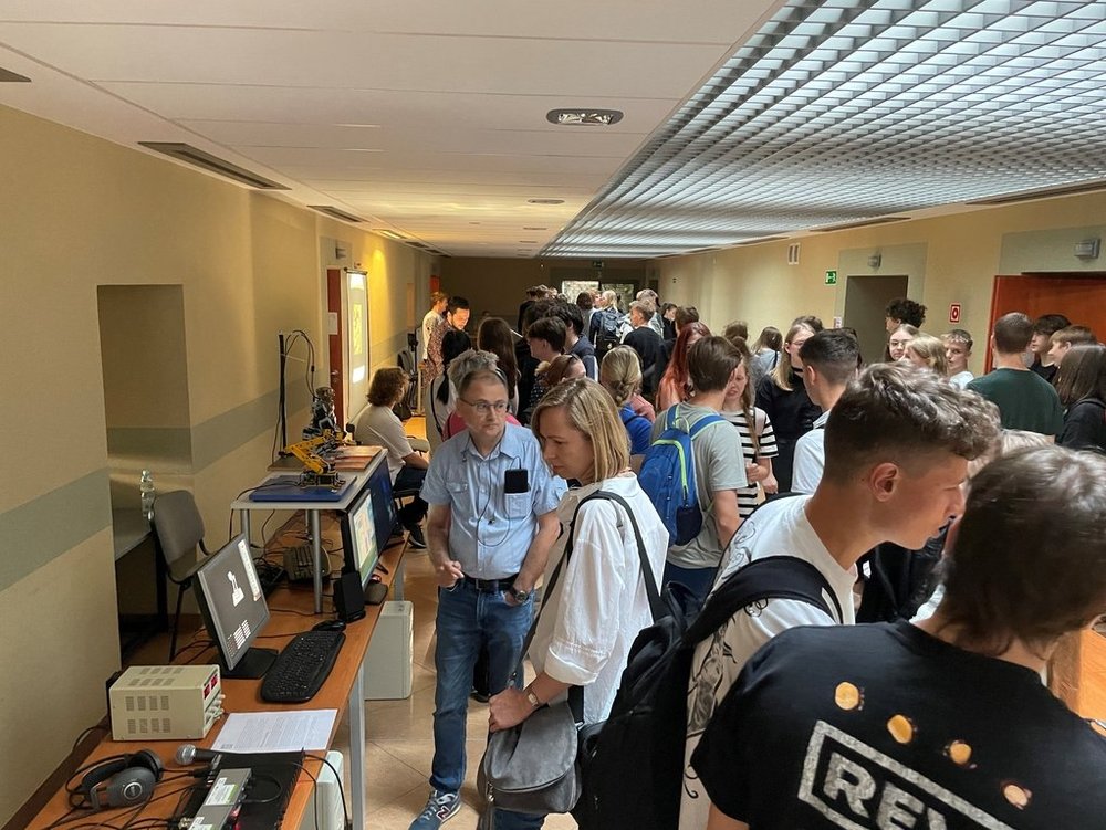 the meeting participants watch physical demonstrations at the stands on the corridor