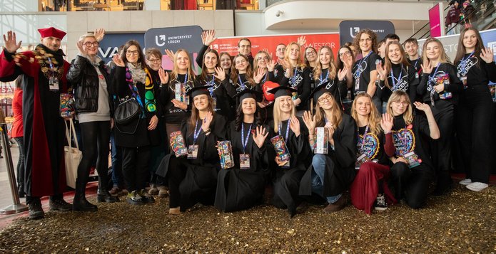 Grupa osób - studenci i Władze UŁ stojący na wielkim sercu ze złotych monet