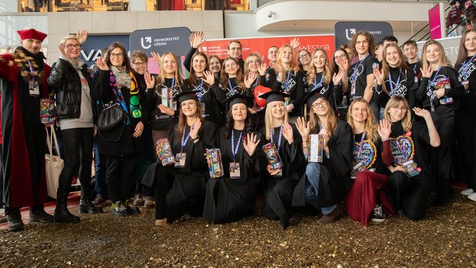 Grupa osób - studenci i Władze UŁ stojący na wielkim sercu ze złotych monet