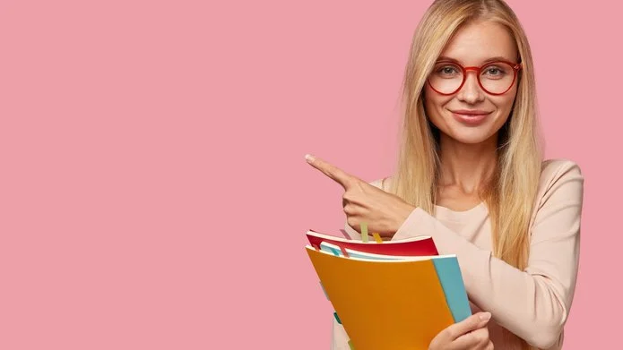 Zdjęcie-uśmiechnięta studentka trzyma trzy kolorowe zeszyty