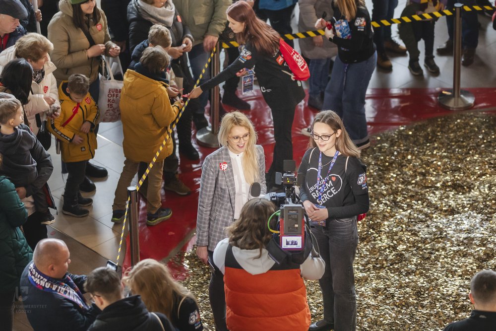 people standing in front of a heart made of gold coins