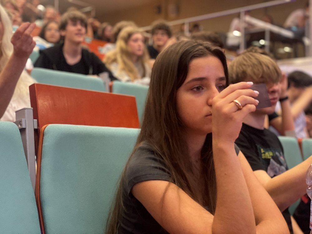 the assembly hall with meeting participants, a brunette girl in the foreground