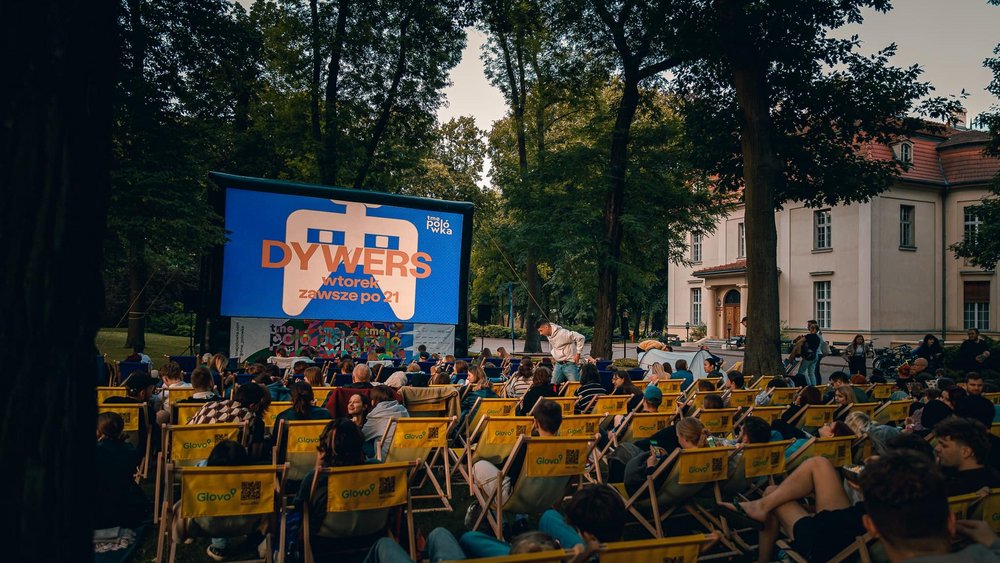 A group of people on deck chairs in a garden watching a film 