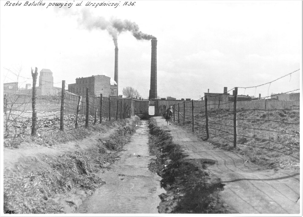 An archival photo of the Bałutka river with a factory chimney