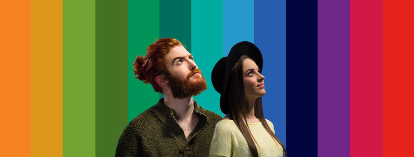 Para młodych ludzi, patrzący w prawy górny róg, na tle kolorowych pasów