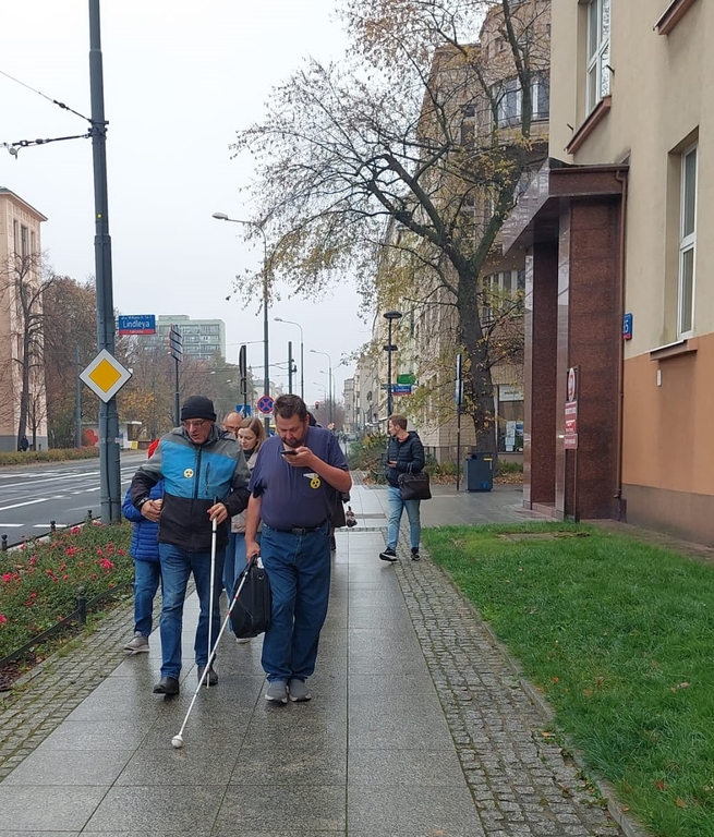 ta sama grupa osób spacerująca wzdłuż ulicy Narutowicza